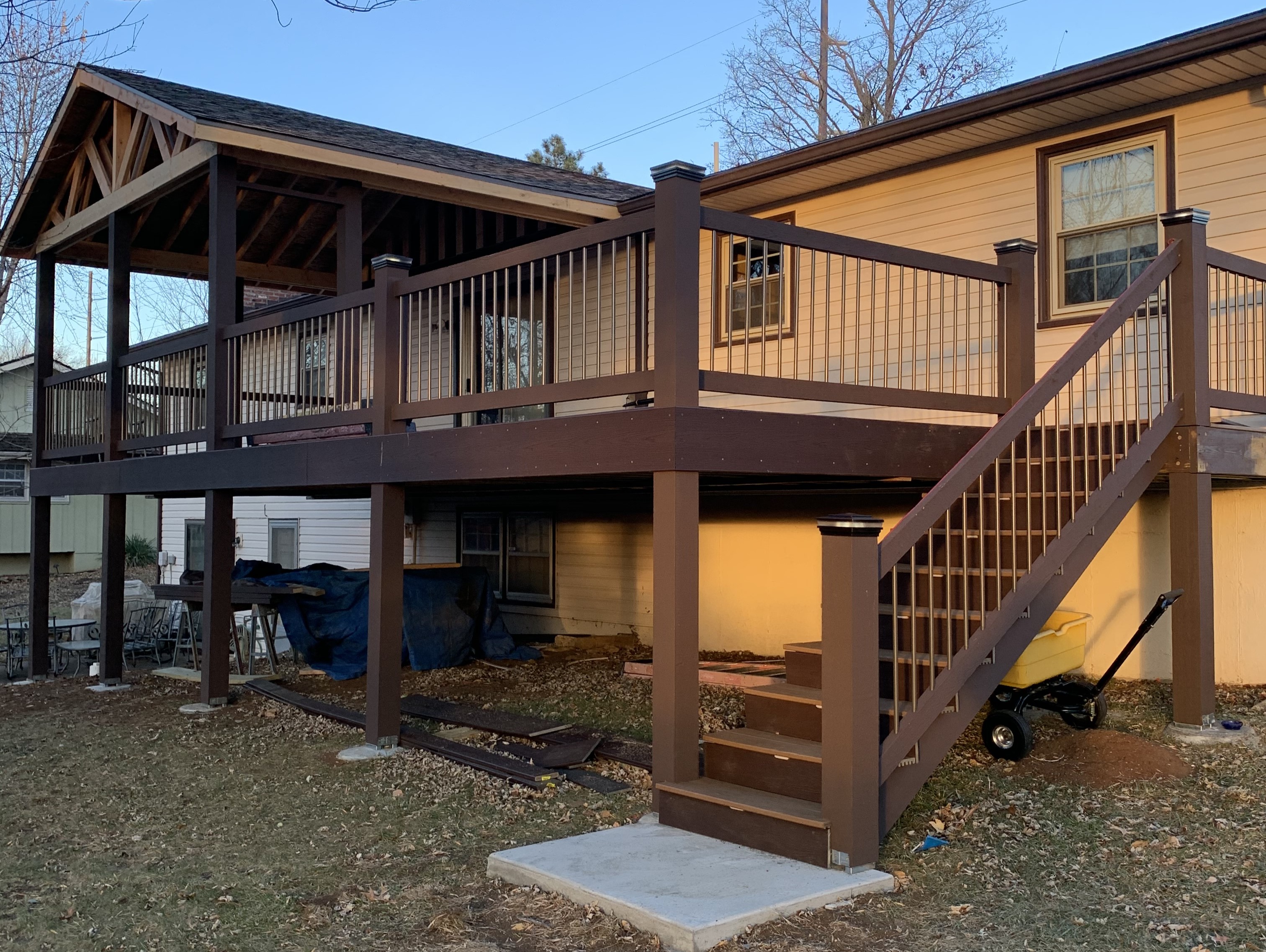 brown deck balcony with a roof and stairs that have lighting