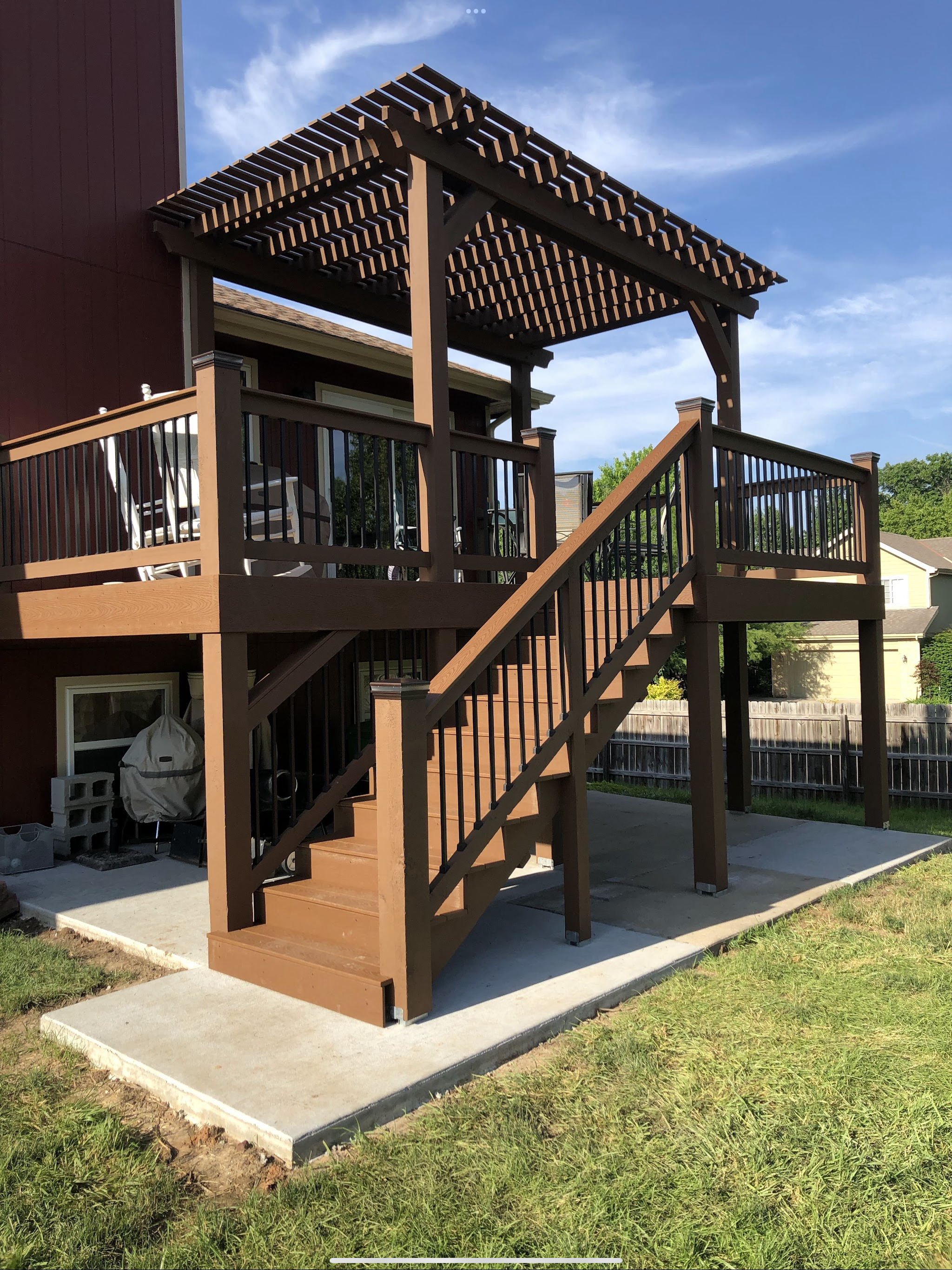 Brown deck balcony with a pergola and stairs over a new concrete slab