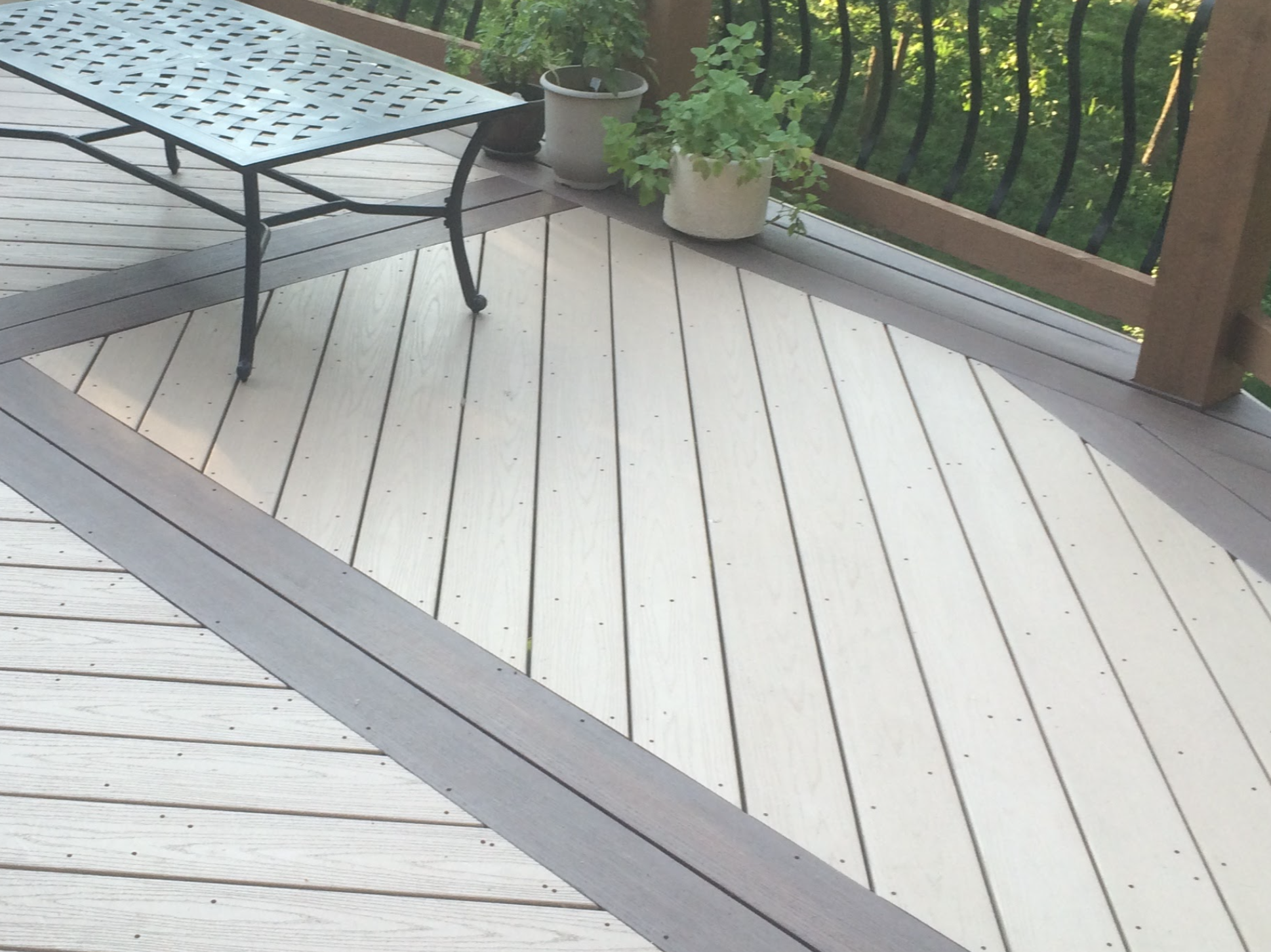 white and gray deck flooring with a glass table in the corner and brown railing with black
