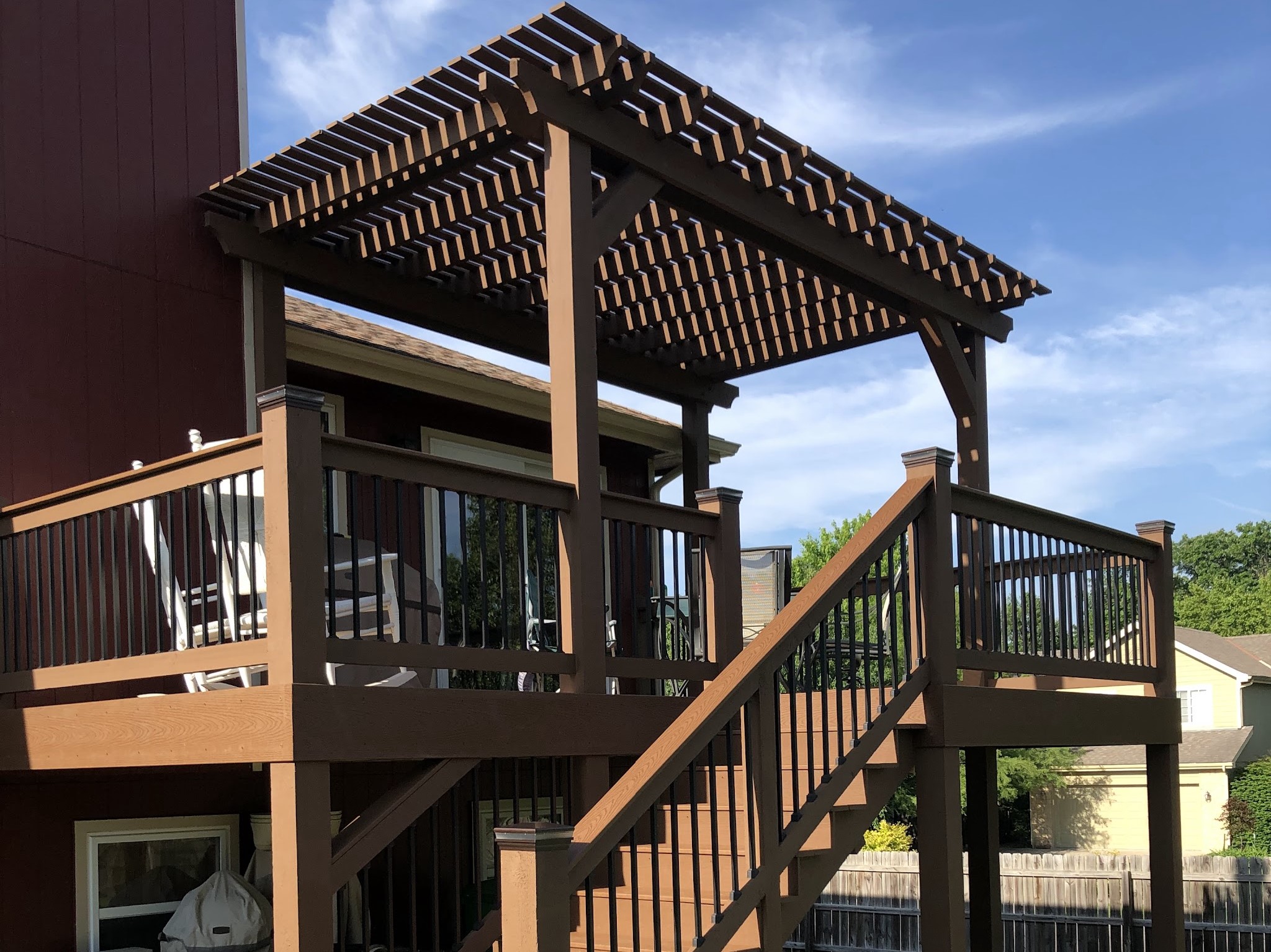 brown deck with pergola stairs and chairs on the deck