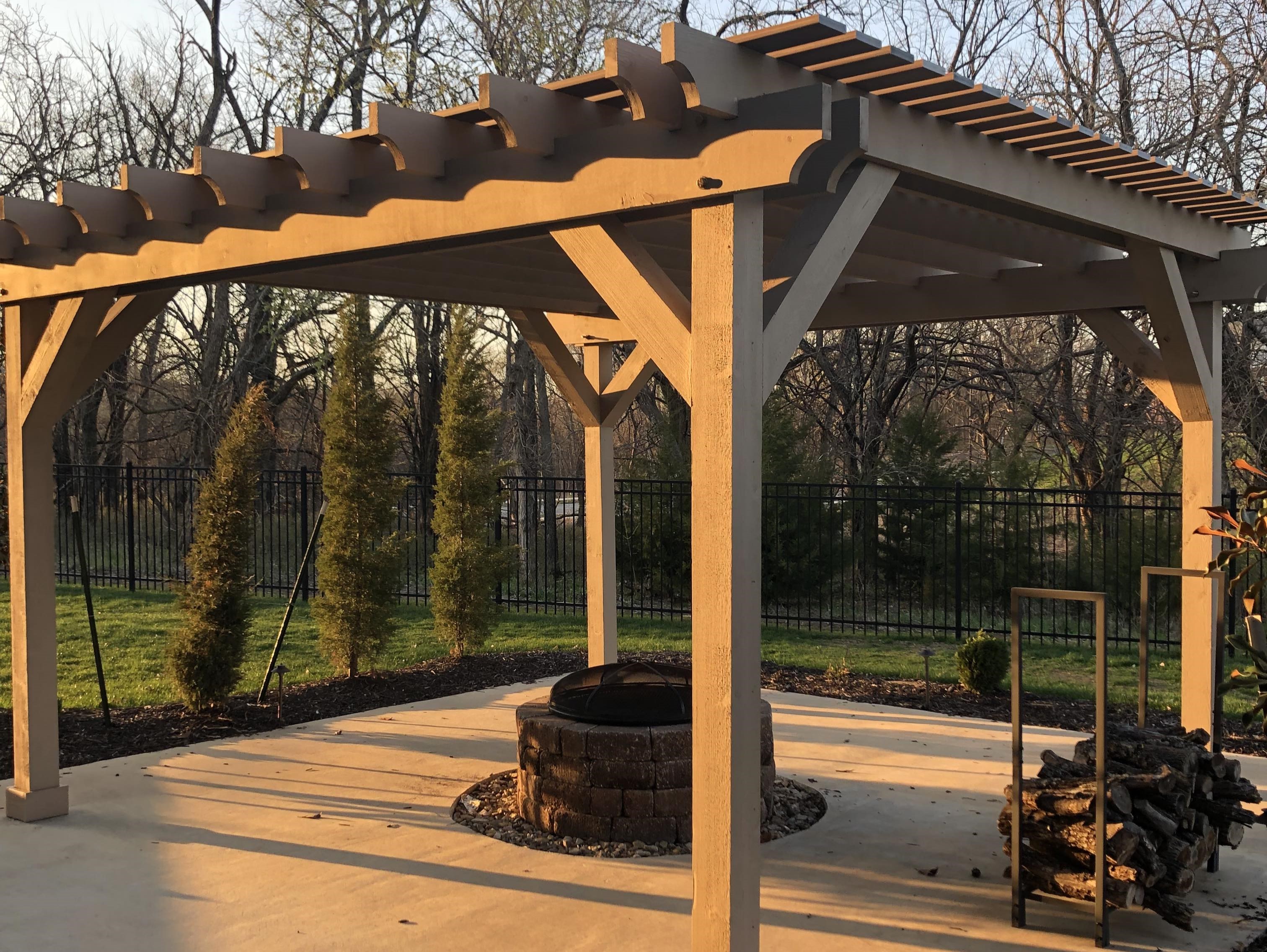 light brown pergola over a fireplace and concrete patio