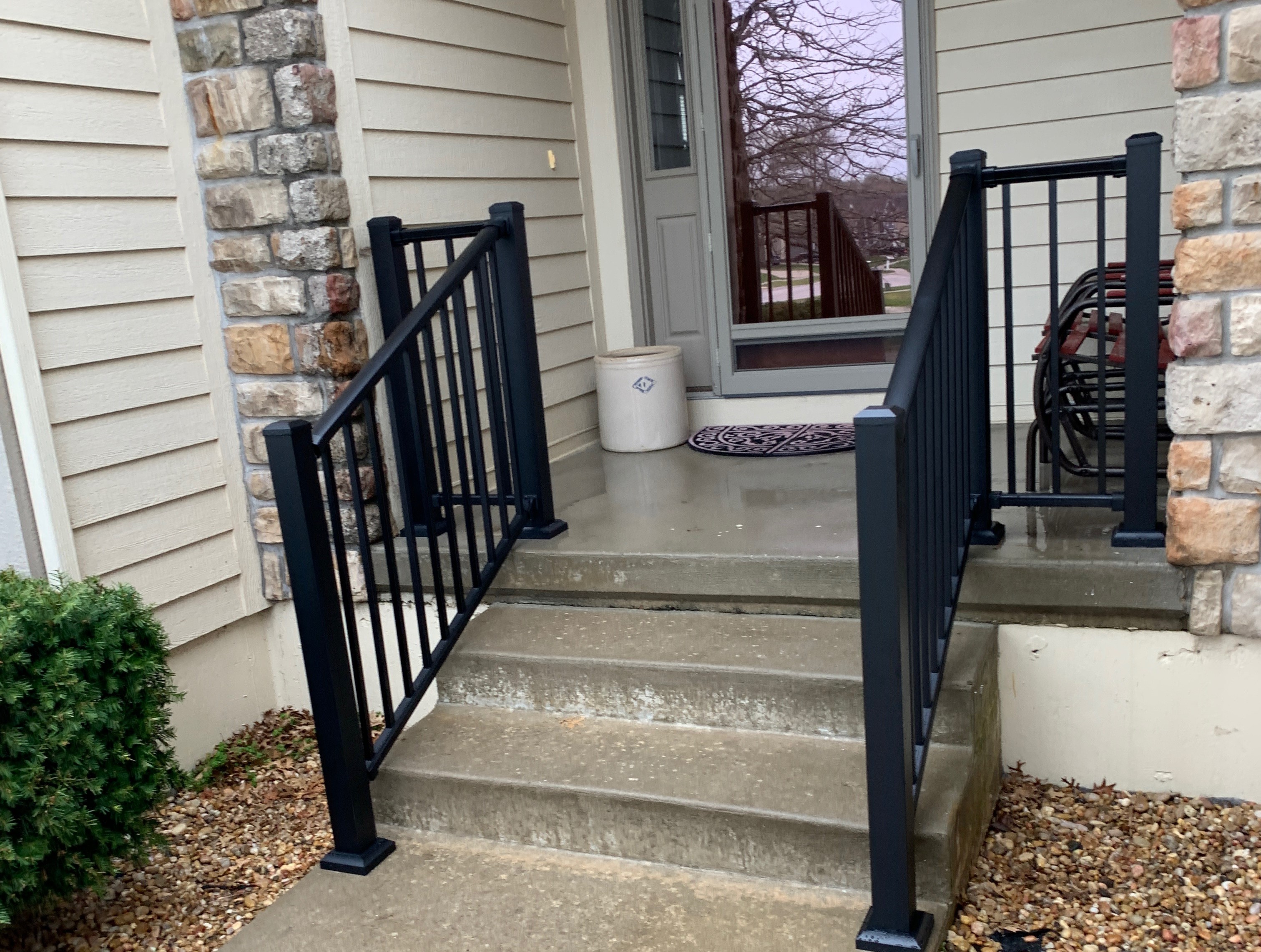 concrete porch with stairs and black railing
