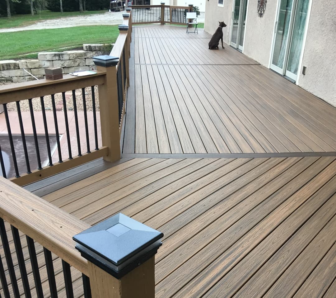Dog sitting on top of a deck floor staring inside the house